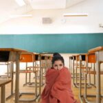 Classe scolastica vuota e donna avvolta in una coperta