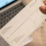 Un assegno e, sullo sfondo, un computer portatile