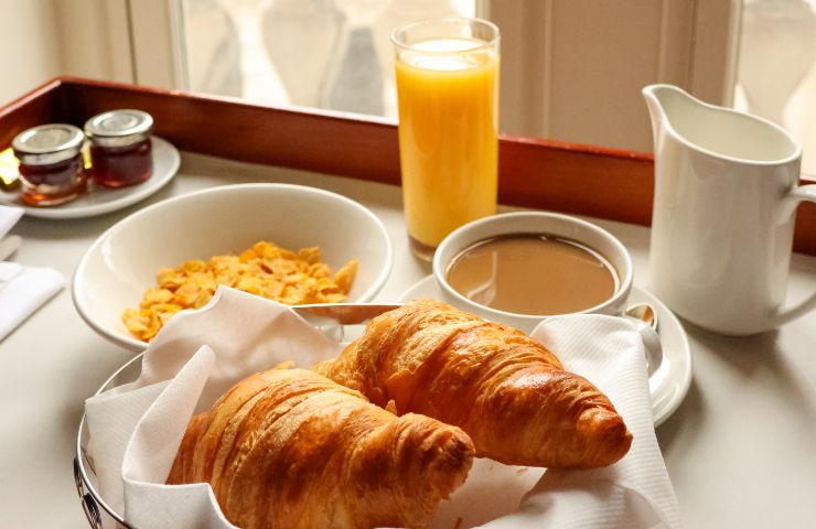colazione con cornetto, cappuccino e succo d'arancia