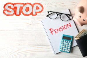 pensione, calcolatrice, salvadanaio a forma di maialino e scritta stop